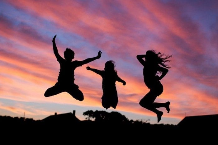 Children jumping in the air during a sunset