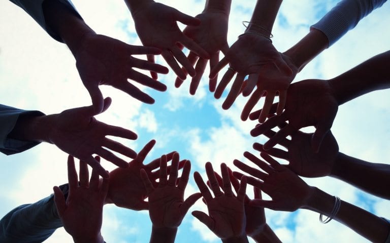 Closeup portrait of hands together in a circle against sky in background