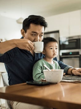 Father drinking coffee with son on computer