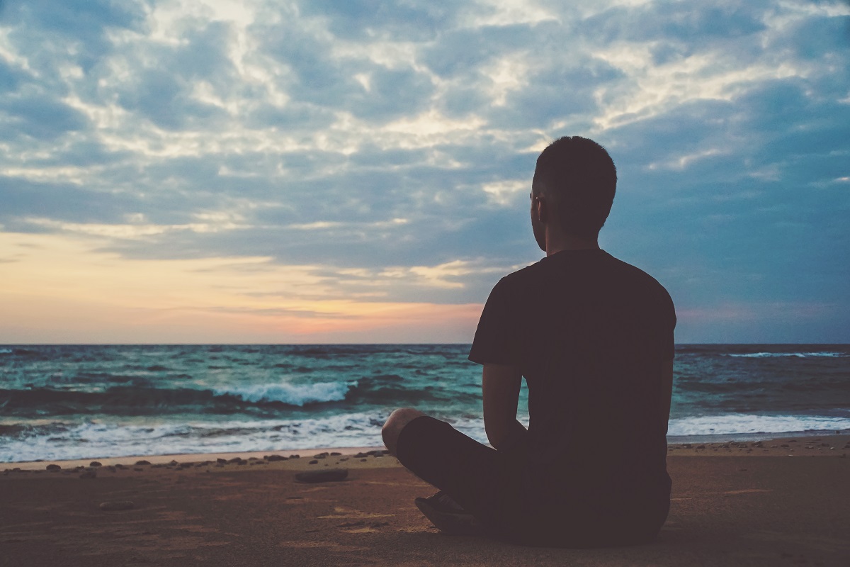 man meditating by beach