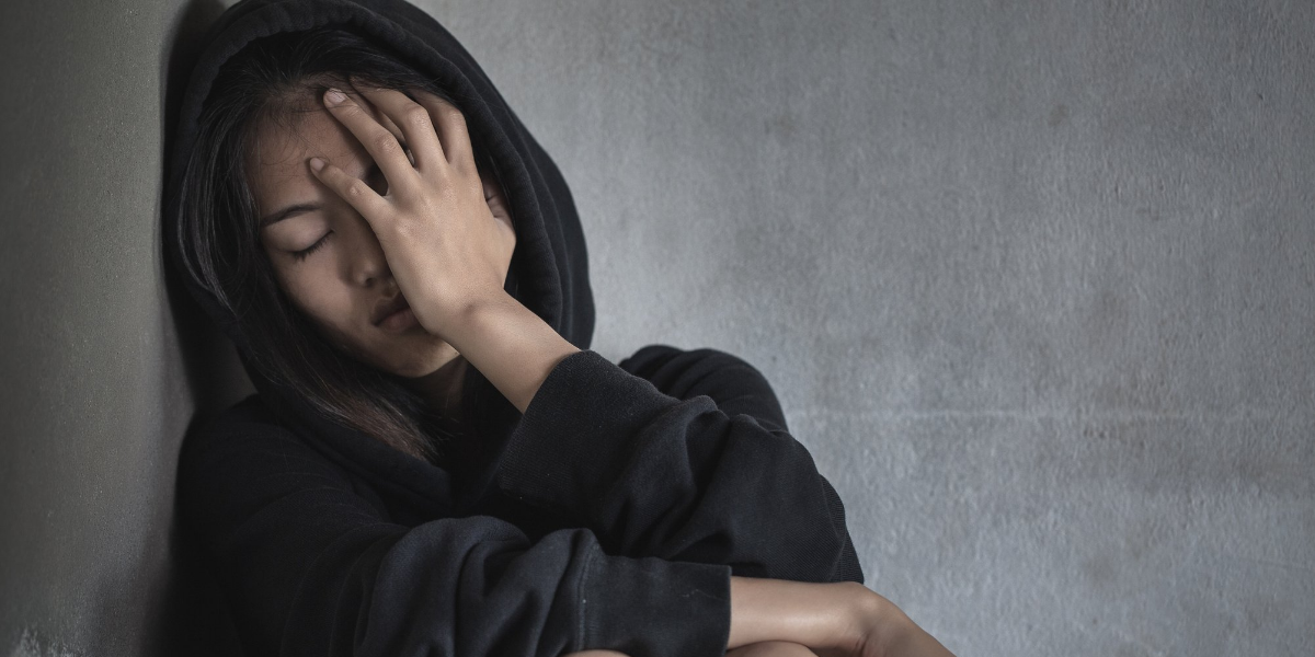 depressed woman putting her head against a wall