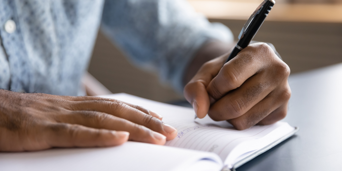 man writing on paper