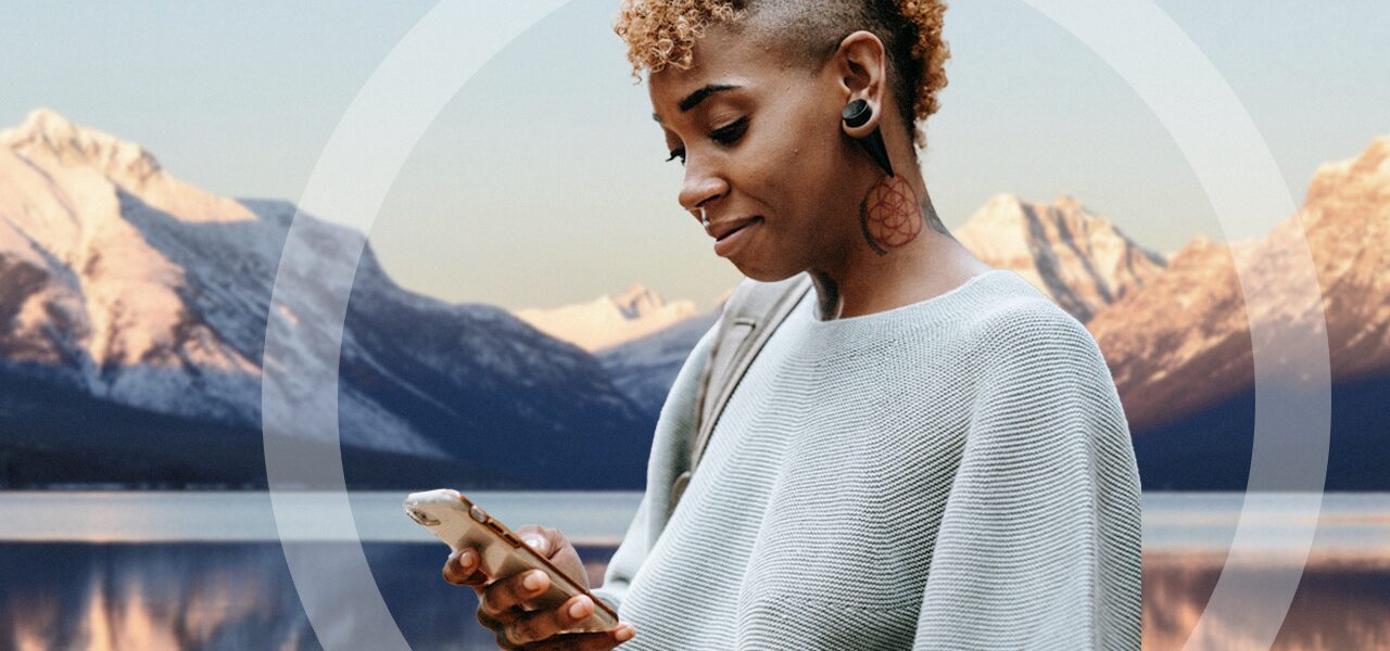 Woman with a mountain background, looking at her phone looking for Online addiction and mental health treatment