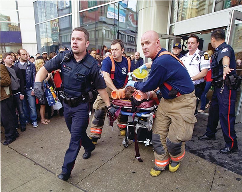 first responders carrying an injured patient with haste in the middle of the crowd