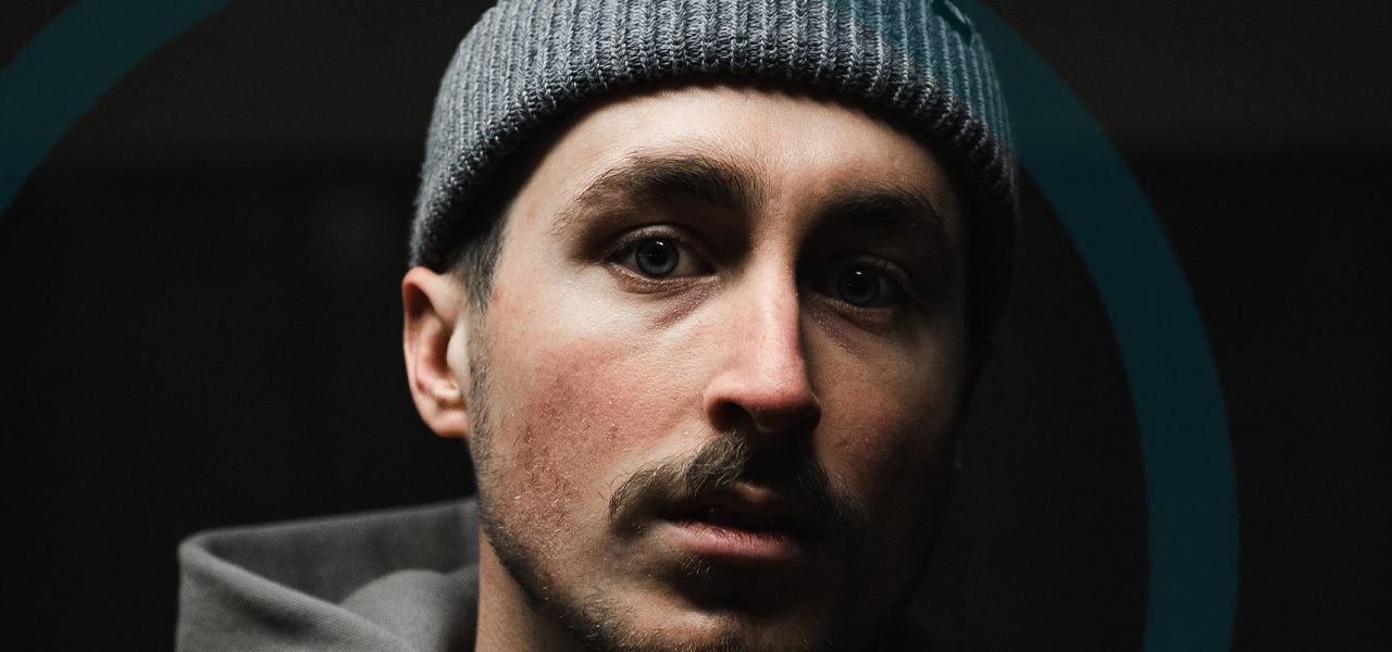 Man with a beanie looking straight into the camera after drinking