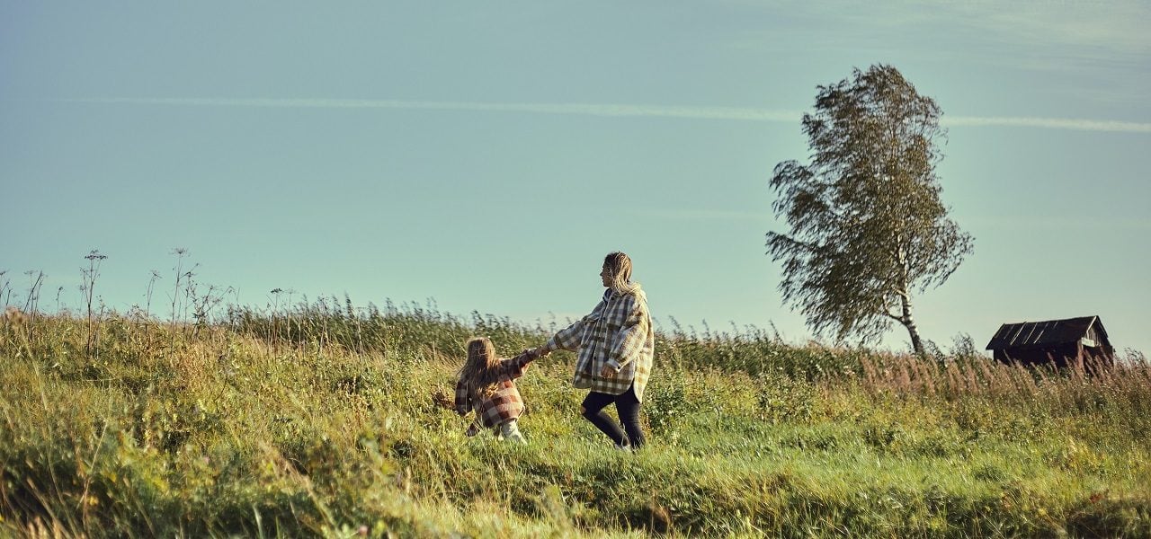 Daughter pulling mother in green field