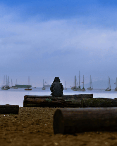 person with a jacket and hood peering out over a dock