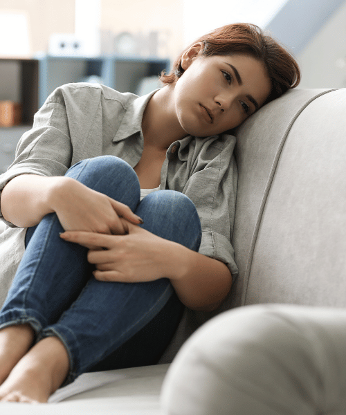 woman lying on couch holding her knees in